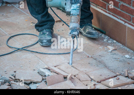 Terrasse Doppelboden, in Werke zu platzieren wtaerproofing darunter und ein Arbeiter in der foregournd mit einem konkreten Bohrwerkzeug Stockfoto