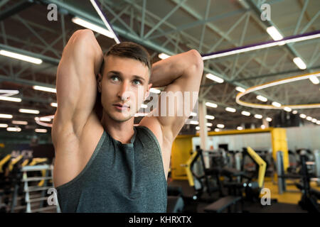 Portrait von gutaussehenden jungen Mann verbiegen Armmuskeln posing suchen, während Sie im modernen Fitnessraum, Kopie Raum Stockfoto