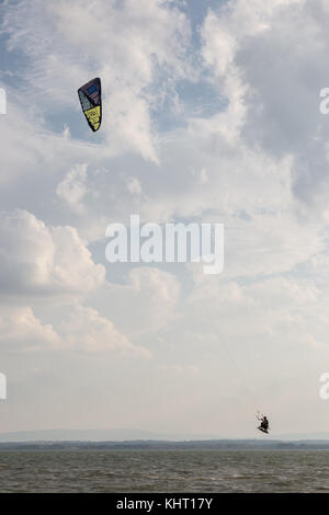 Ein Mann fliegen mit einem Kite surfen Sie auf See, mit einer tiefen, bewölkter Himmel im Hintergrund Stockfoto