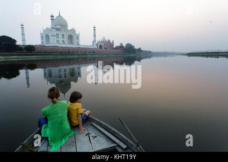 Frau in Grün und Junge im gelben T-Shirt oben Fischerboot an der Reflexion des Taj Mahal in der Dämmerung auf der Suche sitzen, Uttar Pradesh, Agra. Stockfoto