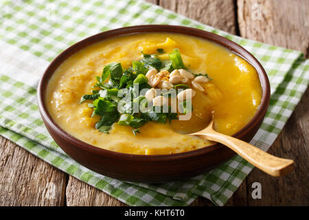 Thai curry Kürbiscremesuppe mit Erdnüssen, Kokosmilch und Koriander close-up in einer Schüssel auf dem Tisch. Horizontale Stockfoto