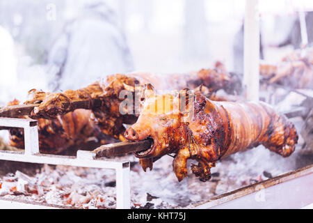 Traditionell Spanferkel auf einem sich drehenden Spieß mit Feuer und Rauch. Stockfoto