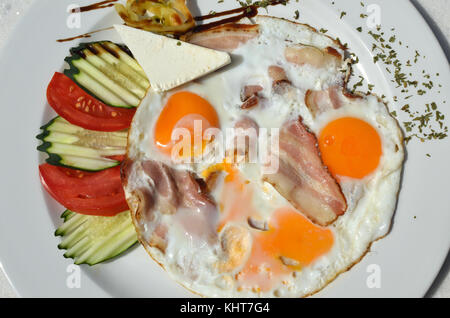 Platte dekoriert mit Frühstück - Spiegeleier, Speck und frischem Gemüse serviert. Stockfoto