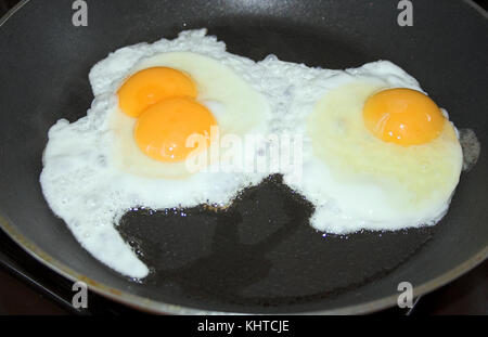 Eier in einer Pfanne mit einem Doppel-Eigelb-Ei. Dieses Bild wurde auch in meinen anderen „Eiern mit einem digitalen Twist-Bild“ verwendet, die auf dieser Website aufgeführt sind. Stockfoto