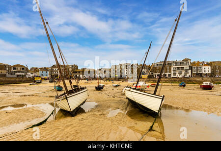 Geerdete Boote in St Ives Hafen bei Ebbe mit Blick in Richtung der Stadt Geschäfte. Stockfoto