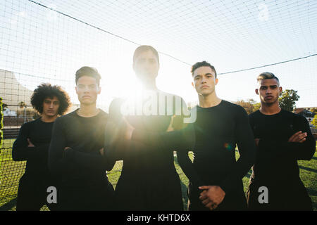 Junge Fußballmannschaft, die zusammen in einer Schlange auf dem Fußballfeld steht. Fußballspieler im Training. Stockfoto