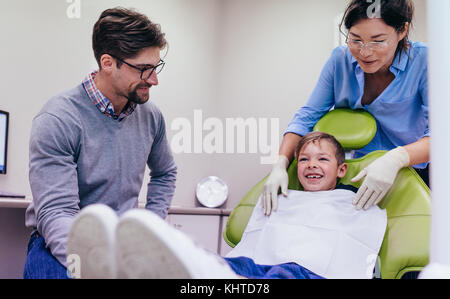 Zähne Checkup beim Zahnarzt. Lächelnd kleiner Junge sitzt auf zahnarztstuhl in der zahnmedizinischen Klinik mit Arzt und Krankenschwester. Stockfoto