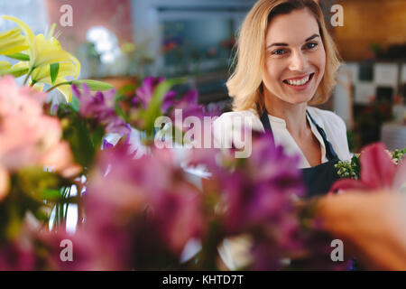 Lächelnd Blumenhändler in Ihrem Shop zu arbeiten. Schöne kaukasische Frau im Blumenladen. Stockfoto