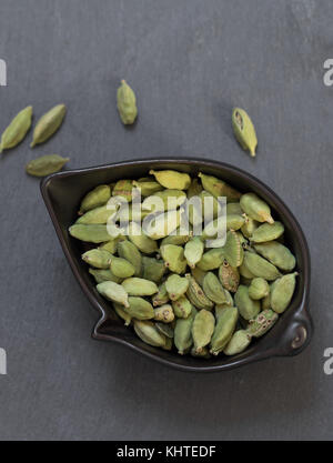 Kardamom in der Schale auf grauem Stein Hintergrund Stockfoto