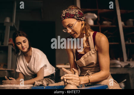 Frau Töpfer die Kunst des Pot. Frauen arbeiten an der Töpferscheibe Ton Objekte in der Werkstatt. Stockfoto