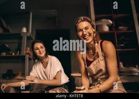 Zwei Frauen, die tongefäße auf der Töpferscheibe in der Werkstatt. Freundliche Frauen genießen die Kunst der Topf auf der Töpferei. Stockfoto