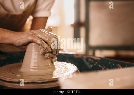 Potter einen Ton Objekt auf Keramik Rad in der Werkstatt. Handwerker molding Clay mit den Händen auf die Töpferei Rad. Stockfoto