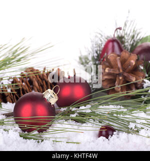 Weihnachtsschmuck und Tannennadeln im Schnee auf weißem Hintergrund Stockfoto