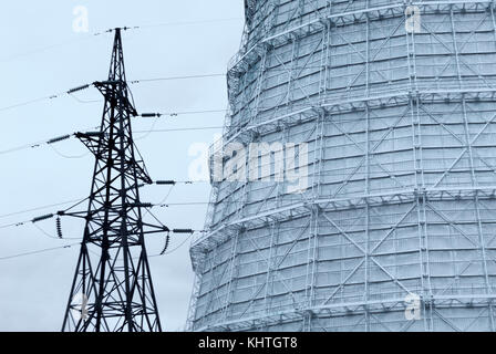 Unterstützung der Hochspannungs-Gleichstrom-Übertragungsleitung vor dem Hintergrund der ein Fragment eines riesigen kühlturm Stockfoto