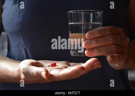 Gesundheitswesen & Arzneimittel. Frau mit einem Gel Kapsel mit einem Glas Wasser. Stockfoto