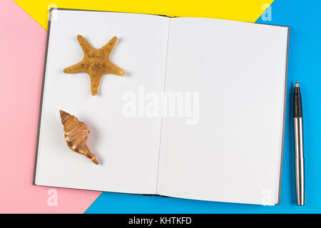 Notebook mit Muscheln und Seesterne auf blauem Hintergrund. Urlaub, Reise Konzept Stockfoto