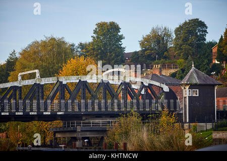 Kanal Boote schwimmend auf dem Fluss Weaver mit goldener Herbst Bäume in die Landschaft und die Stadt Northwhich Swing Bridge im Hintergrund, Northwich i Stockfoto