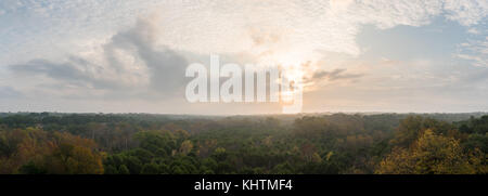 Sun shinning durch Wolken mit Nebel über Wald im Herbst Saison Stockfoto