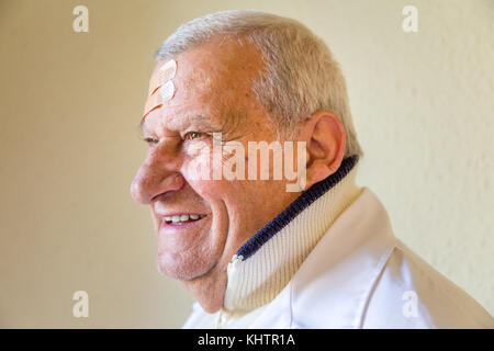 Alte Doktor mit Flecken auf der Stirn lächelnd Stockfoto