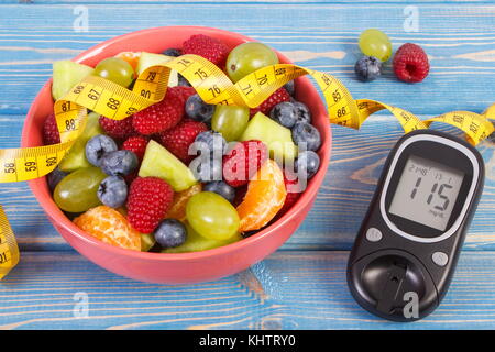Salat von frischen Früchten, Blutzuckermessgerät mit Ergebnis der Messung Blutzucker und Maßband, Konzept der Diabetes, Diät, Abnehmen, gesunde Lebensführung und Stockfoto