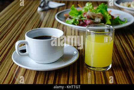 Tasse Kaffee mit Glas Saft auf den Tisch für das Frühstück. Stockfoto