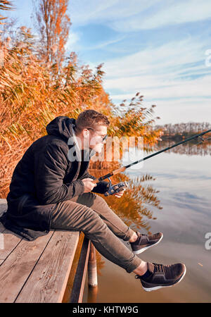 Mann geht Angeln im Herbst von der Brücke über den Fluss Stockfoto