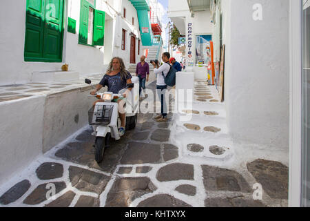 Lokale Mann auf Roller fährt auf typische Gasse, Mykonos Stadt, Mykonos, Kykladen, Ägäis, Griechenland Stockfoto