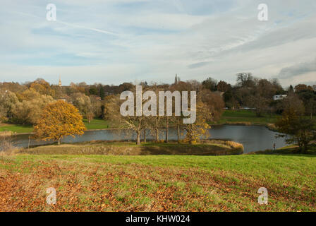 Blick über das Modell bootfahren Teich, Hampstead Heath mit warmen Farben des Herbstes auf den See, Bäume und Wiese. highgate in der Ferne. Stockfoto