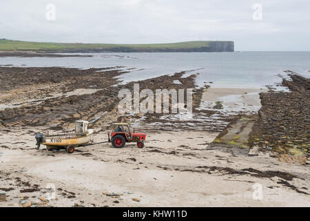 Alter Traktor, der Fischerboot über den Strand zum Meer zieht, Birsay, Orkney, Schottland, Großbritannien Stockfoto
