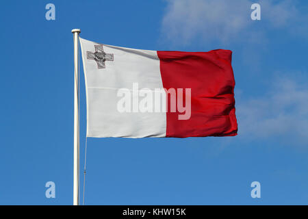 Die Nationalflagge von Malta fliegt in einem starken Wind vor einem blauen Himmel Hintergrund, mit dem George Cross in der Ecke. Maltesische Farben. Stockfoto