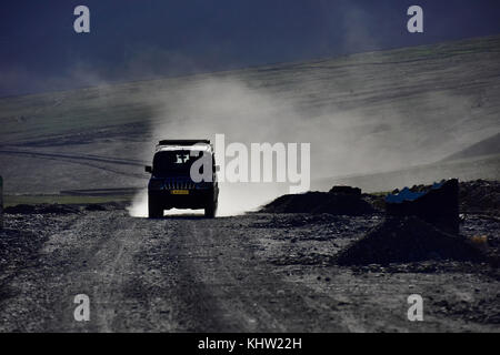 Silhouette von Auto Jeep auf einem Berg Straße in goldenen Staub, Dawn. Stockfoto