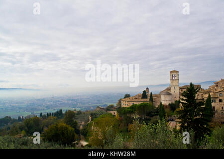 Assisi. Blick von der Piazza Santa Chiara während einer November nebligen Tag. Auf Hintergrund Heiligtum der Santa Maria degli Angeli, bekannt als porziuncola Stockfoto