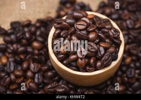 Hölzerne Schüssel mit gerösteten Kaffeebohnen auf rustikalen Hintergrund. Stockfoto