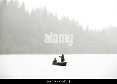 Zwei Fischer im Boot im schweren Regen auf Loch in Schottland Stockfoto