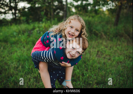 Portrait der junge Schwester, die ein Huckepack im Feld Stockfoto
