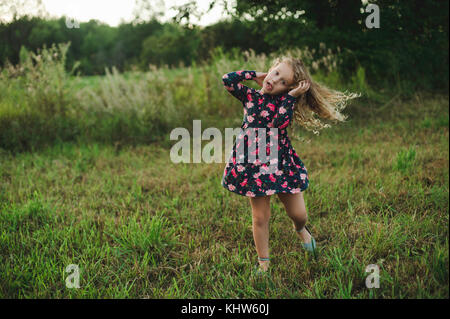 Blonde Mädchen laufen und ziehen ein Gesicht im Feld Stockfoto