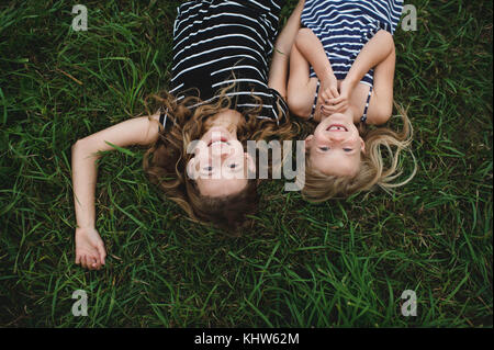 Overhead kopfüber Portrait von Mädchen und ihre Schwester liegen auf Gras Stockfoto