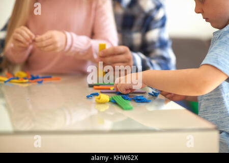 Vater, Sohn und Tochter, am Tisch sitzen, spielen mit Knetmasse, mittlere Partie Stockfoto