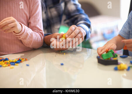 Vater, Sohn und Tochter, am Tisch sitzen, spielen mit Knetmasse, mittlere Partie Stockfoto