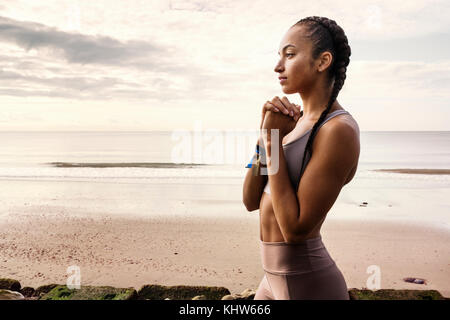 Junge Läuferin Vorbereitung mit Hände zusammen am Strand laufen Stockfoto