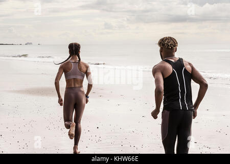 Ansicht der Rückseite des jungen männlichen und weiblichen Läufern laufen am Strand Stockfoto