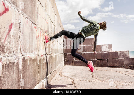 Junger Mann, Free Running, Outdoor, auf Seite der Wand Stockfoto