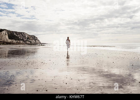 Junge Frau Strand entlang läuft Stockfoto