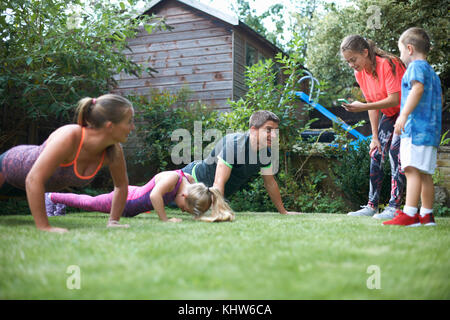 Familie trainieren in Garten, Push-ups Stockfoto