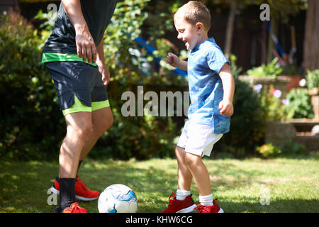 Vater und Sohn Fußball spielen im Garten Stockfoto