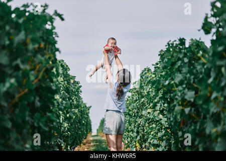 Woman Holding up baby Tochter im Weinberg, Bergerac, Aquitanien, Frankreich Stockfoto