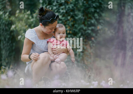 Frau hockend mit Baby Tochter im Park, Chenonceaux, Loire Tal, Frankreich Stockfoto