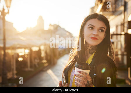 Junge Frau im Freien, Kaffeetasse, Tattoos auf Hals und Händen Stockfoto