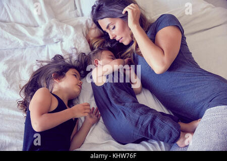 Mutter und zwei kleinen Kindern, liegend auf dem Bett Stockfoto