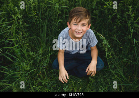 Jungen auf der Suche oben an der Kamera auf der grünen Wiese Stockfoto